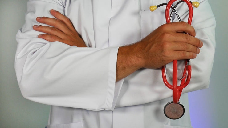 person in white coat holding stethescope