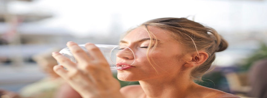 blonde woman drinks glass of water