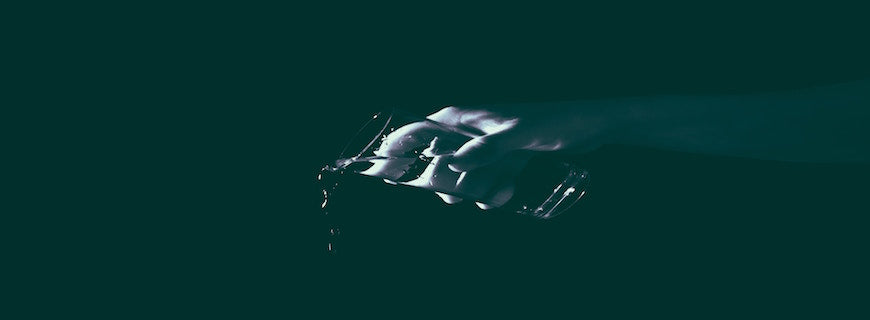 an arm, on black background, pouring out a glass of water