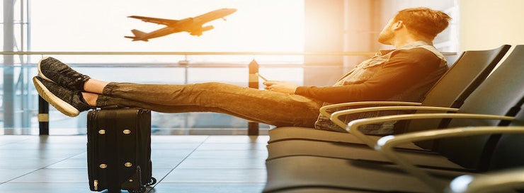 man in airport lounge reclining as a plane ascends in background