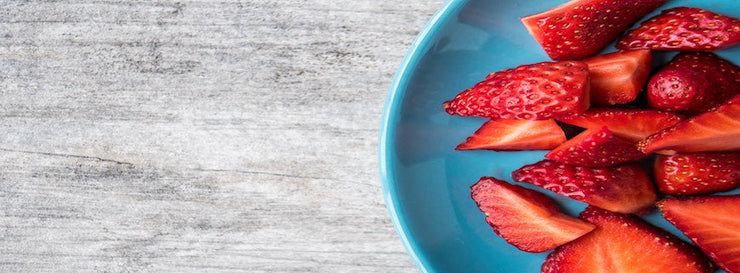 sliced strawberries arrayed on a blue plate