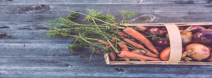 basket of healthy food including carrots and onions