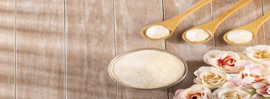 An image of collagen powder in a bowl alongside three laden wooden spoons