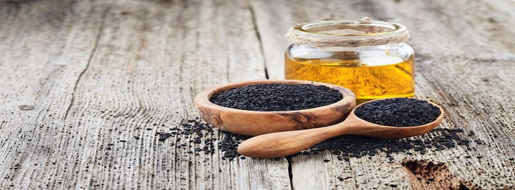 Black cumin oil with seeds on wooden background