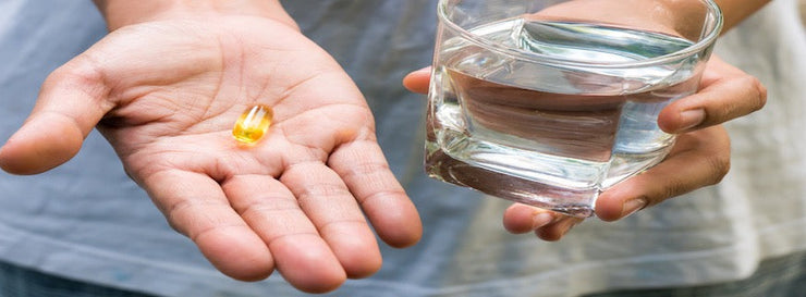 person holding fish oil capsule in the palm of their hand