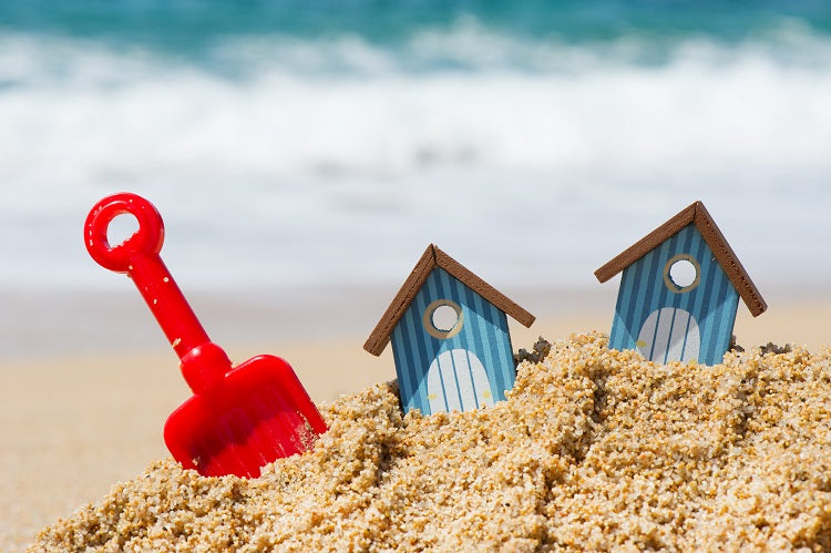 sandcastle with red spade and two toy houses