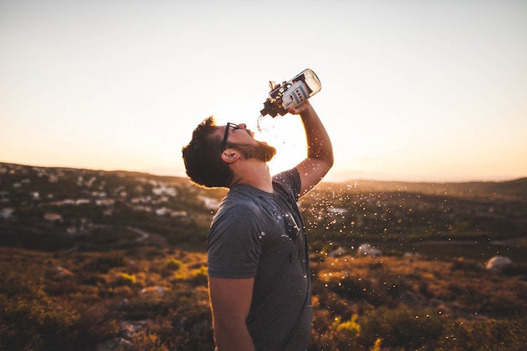 Man outdoors drinking water from bottle