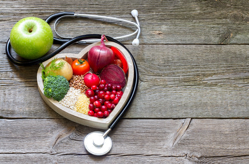 stethescope and a heart shaped dish of fruit and veg